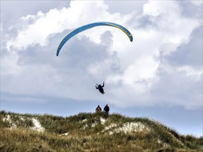 Paraglider flying over dunes on a beach in Vejers