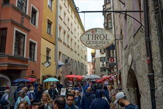 Many tourists in the historic city centre of Innsbruck with a sign Enjoy Tyrol