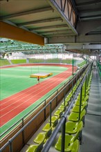 Athlete training on the running track in a stadium with green rows of seats