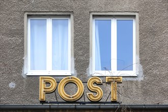 The post no longer goes off here. Climbing plants growing on a post office logo of a closed post office branch