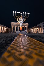 Menorah in front of the Brandenburg Gate at night with festive lighting