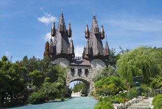 A fairytale castle with pointed towers surrounded by a lush garden landscape
