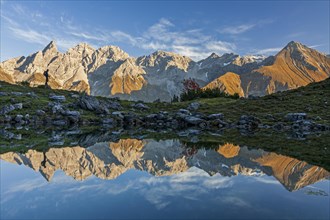 Hiker reflected in mountain lake in front of mountains, evening light, Guggersee, Allgaeu Alps,