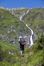 Mountaineer in front of a waterfall, Berliner Hoehenweg, Zillertal Alps, Tyrol, Austria, Europe