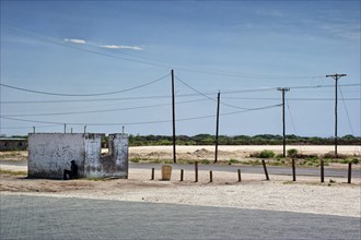 Lonely man sits in the shade of a petrol station in Guamare, Botswana, Africa