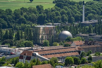 Industrial complex with cooling tower and factory buildings, surrounded by green spaces, gasometer,