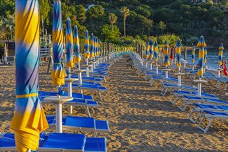 Sun loungers and parasols on Straccolignino beach at sunrise, near Capoliveri, Elba, Tuscan