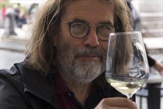 Portrait of a man with a beard and glasses, toasting with a wine glass, Genoa, Italy, Europe