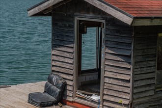 Old abandoned fishing shack and dock floating on surface of lake