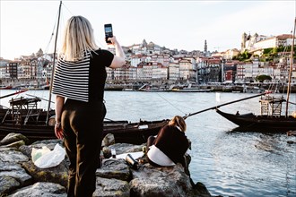 Female tourists taking photo of historic Porto city by Douro river, Portugal, Europe
