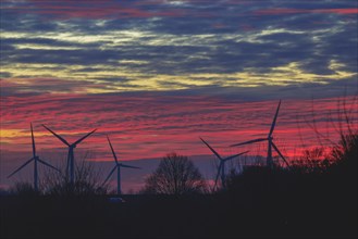 Silhouettes of wind turbines against a red evening sky, open-cast lignite mine, North