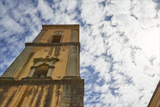 Frog's-eye view of a church tower with the facade in the foreground and cloudy sky, Novara di