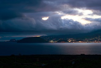 Night view of an illuminated coastal town of Horta under dramatic clouds, Horta, Faial, Azores,