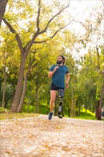 Vertical photo with low angle view of a man with prosthetic leg running outdoors