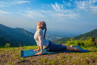 Yoga outdoors, woman practices Ashtanga Vinyasa yoga Surya Namaskar Sun Salutation asana Urdhva