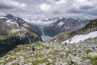 Two mountaineers on hiking trail, view of Schlegeisspeicher, glaciated rocky mountain peaks Hoher