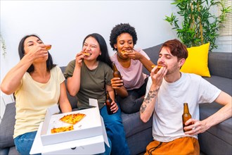Starved friends eating a delicious pizza and drinking beer at home