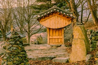 Small wooden oriental building with tiled roof in front of rock wall at countryside roadside park