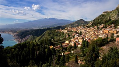 Mount Etna, panoramic view of a coastal town with mountains in the background and clear sky,
