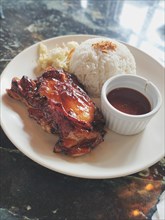 Chicken inasal with rice and atchara or papaya salad served with barbecue sauce, authentic Filipino