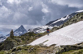 Mountaineer on a rocky hiking trail in a snowfield, Berliner Hoehenweg, mountain landscape with