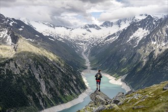 Mountaineer on a rock in front of a mountain panorama, view of Schlegeisspeicher, glaciated rocky