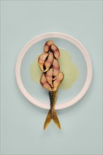 Sliced mackerel on a plate revealing its pinkish inner flesh against the darker outer skin. The