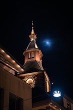 Illuminated church tower with the moon in the background at night, Nagold, Black Forest, Germany,