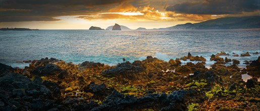 Dramatic volcanic coastal landscape at sunset with glowing sky and cliffs, Madalena, Pico, Azores,