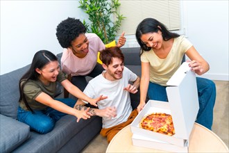 Multi-ethnic starved friends ready to eat a delivery pizza together in the living room at home