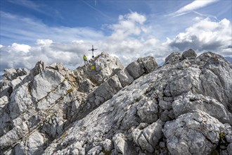 Mountaineer on the rocky summit of the Watzmann Mittelspitze with summit cross, Watzmann crossing,