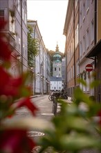 An urban alley with historic buildings and red flowers in the foreground, Salzburg, Austria, Europe
