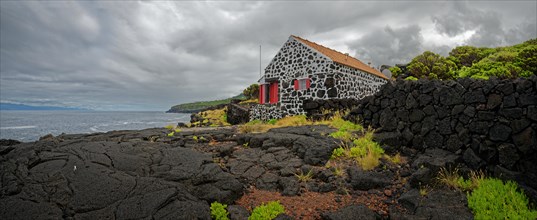 Traditional stone house on the coast with a view of the sea and cloudy sky, North Coast, Santa