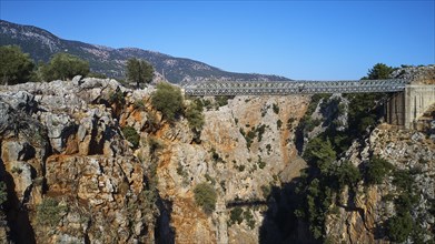 Metallic bridge over a deep gorge surrounded by a mountainous landscape, Aradena Gorge, Aradena,