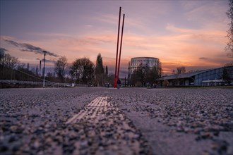 Perspective of a street leading to a sculpture under a colourful evening sky, Enzauen Park,