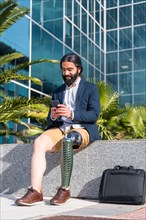 Vertical portrait of a businessman with prosthetic leg using mobile sitting outside a financial