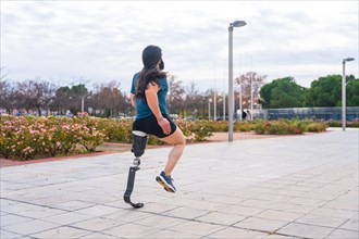 Photo with copy space of a jogger with prosthetic leg running along an urban park