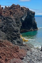 Rugged coastline with steep volcanic cliffs jutting out into the deep blue sea, lava rocks Coastal