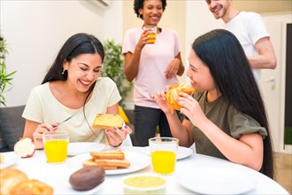 Group of diverse multi-ethnic friends laughing while having breakfast at home