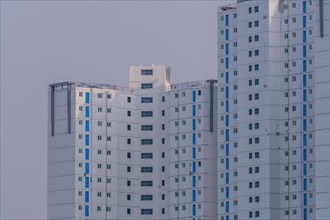 New highrise apartments with unfinished white concrete exterior walls and blue coverings on widow