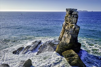 Blue sea waves beat against Nau dos Corvos or Crows nest rock near Peniche peninsula, Portugal at