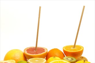 Fresh fruit cut in half with a drinking straw isolated on a white background .orange, grapefruit,
