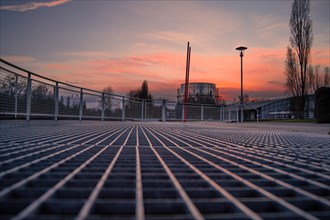 View along a metal lattice onto an empty street at dusk, Enzauen Park, Pforzheim, Germany, Europe