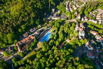 Aerial view of an outdoor swimming pool surrounded by trees and the shadows cast by the low sun,