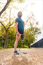 Vertical portrait of a proud sportsman with prosthetic leg standing in a park