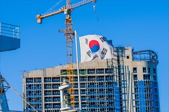Korean flag on flying from a ship in front of a construction crane attached to a building under