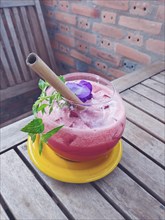 Vertical view of a refreshing watermelon juice with a bamboo straw and an edible flower, healthy