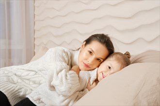 Millenial mother with her little daughter in bed