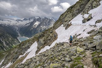 Two mountaineers on hiking trail with snow, view of Schlegeisspeicher, glaciated rocky mountain