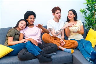 Diverse friends watching a movie sitting together on the sofa at an apartment